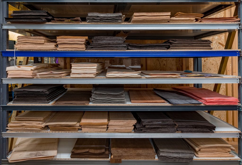 Étagère industrielle sur laquelle sont disposé des feuilles de bois d'essences et couleurs variées, atlier d'Inbo